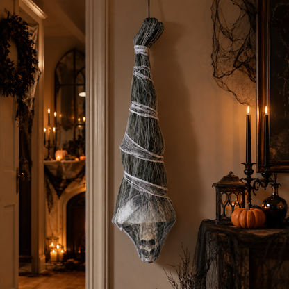 Hanging mummy prop displayed indoors with candles and a pumpkin