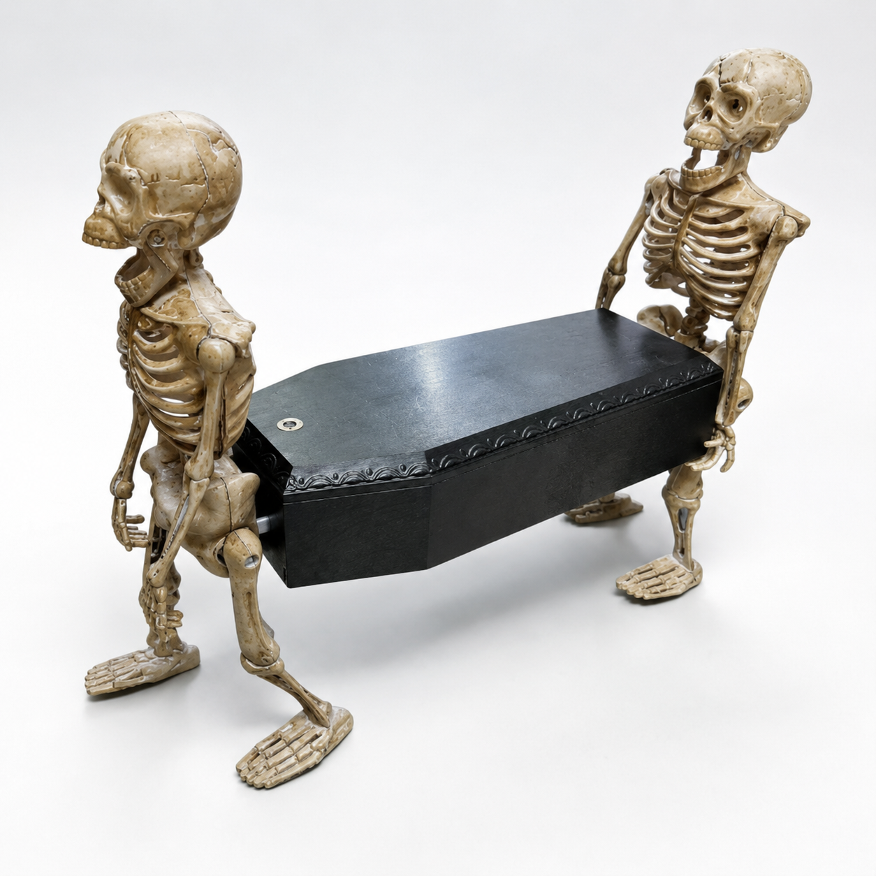 Close view of two walking skeletons carrying a black coffin prop