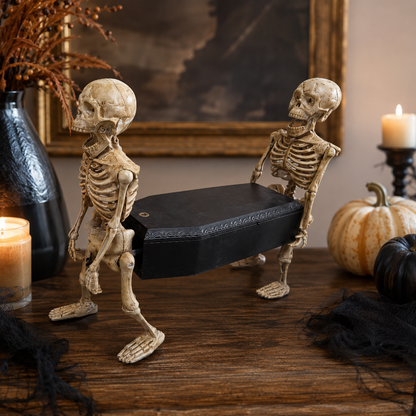 Skeletons carrying a coffin prop displayed with candles and pumpkins