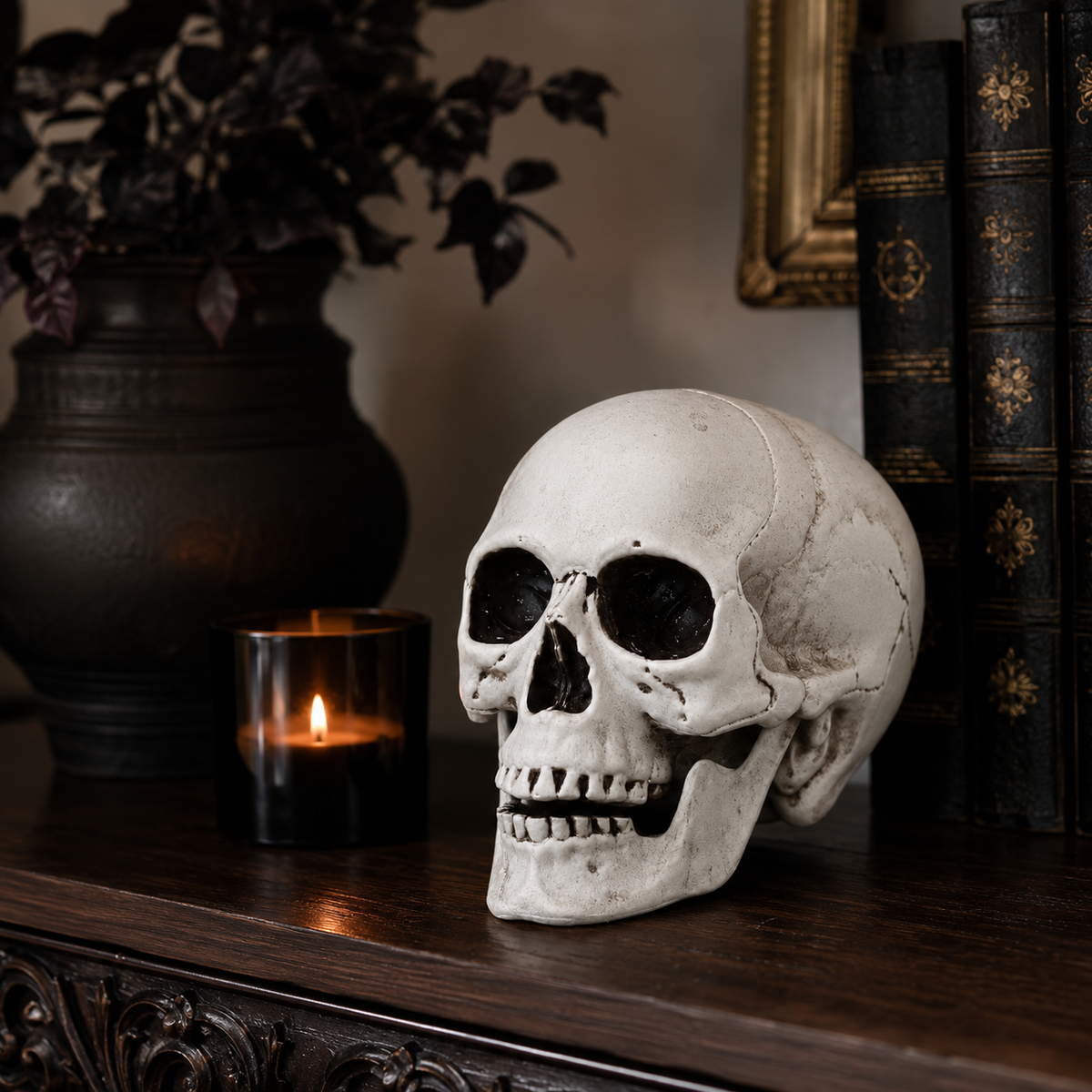 Realistic skull decoration displayed beside a candle and vintage books
