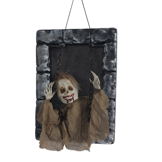 Yellow-robed skeleton tombstone figure hanging from chains in a gray stone frame